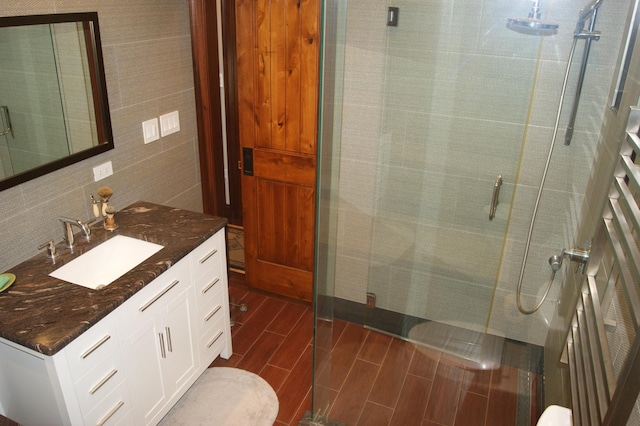 full bathroom featuring vanity, tile walls, a shower stall, decorative backsplash, and wood tiled floor