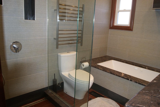 bathroom featuring a tile shower, tile walls, and toilet