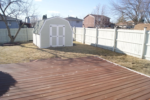 wooden deck with a yard, a shed, an outdoor structure, and a fenced backyard