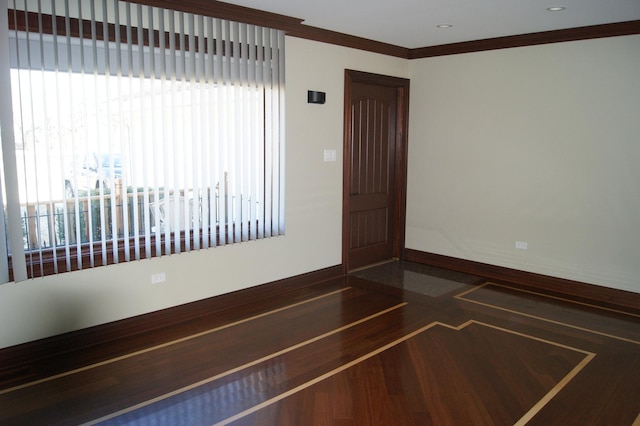 spare room featuring ornamental molding, baseboards, and wood finished floors