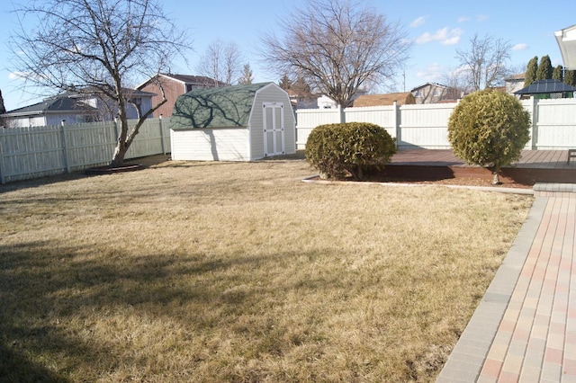 view of yard with an outbuilding, a fenced backyard, a wooden deck, and a shed