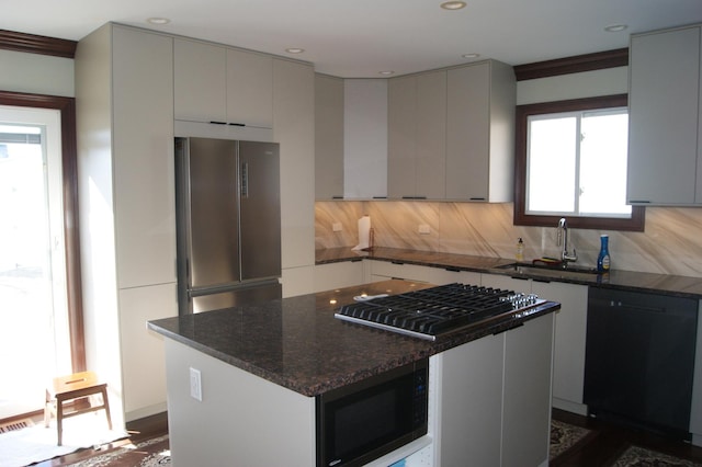 kitchen with black appliances, plenty of natural light, a kitchen island, and decorative backsplash