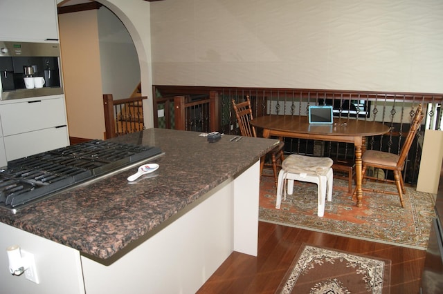 kitchen with arched walkways, stainless steel appliances, white cabinets, modern cabinets, and dark wood finished floors