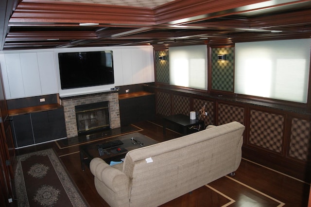 living room with a brick fireplace, coffered ceiling, and wood finished floors