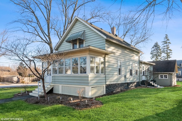 view of side of home with a yard, entry steps, a chimney, and a sunroom