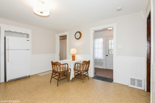 dining area with a wainscoted wall and visible vents