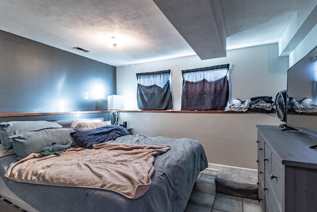 bedroom with visible vents, a textured ceiling, and baseboards