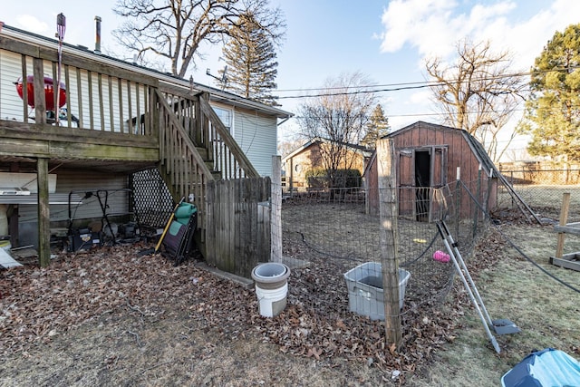 view of yard with an outbuilding, fence, stairway, a wooden deck, and a storage unit