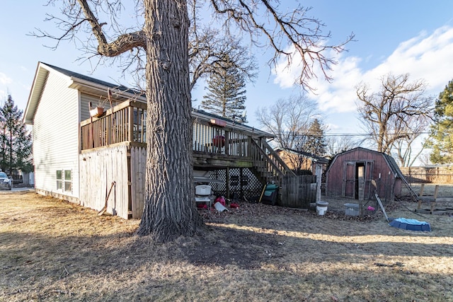 view of property exterior featuring stairs, fence, a wooden deck, a shed, and an outdoor structure