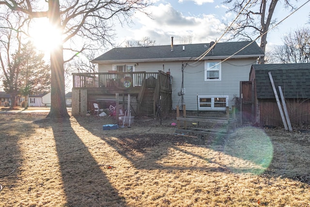 rear view of house with a shingled roof, a deck, and stairs