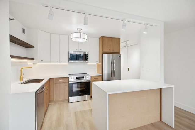 kitchen with open shelves, stainless steel appliances, light wood-style floors, a sink, and a peninsula