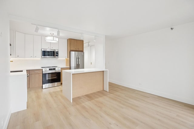 kitchen with light countertops, light wood-style flooring, appliances with stainless steel finishes, a kitchen island, and baseboards