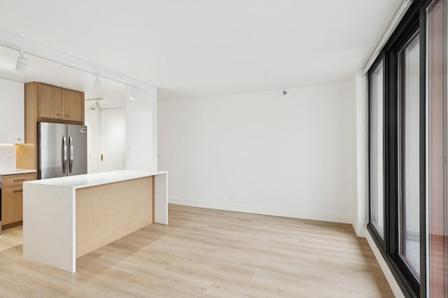 kitchen featuring freestanding refrigerator, baseboards, light countertops, and light wood finished floors