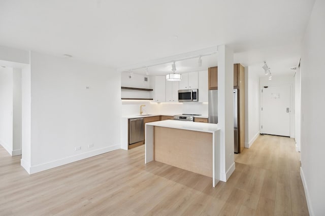 kitchen featuring open shelves, light wood-type flooring, stainless steel appliances, and light countertops