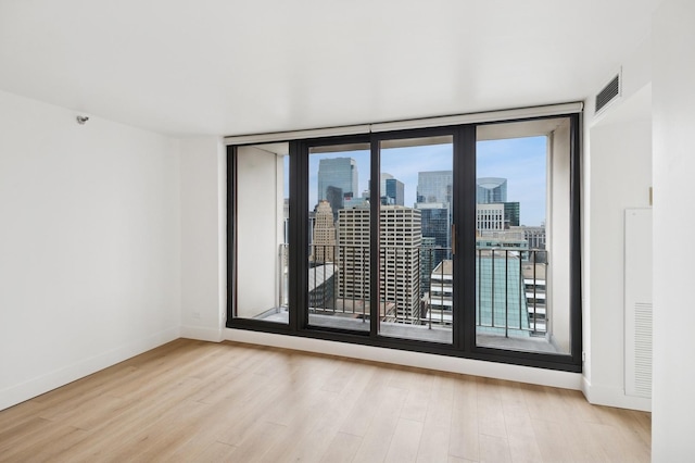 spare room featuring baseboards, a view of city, visible vents, and wood finished floors