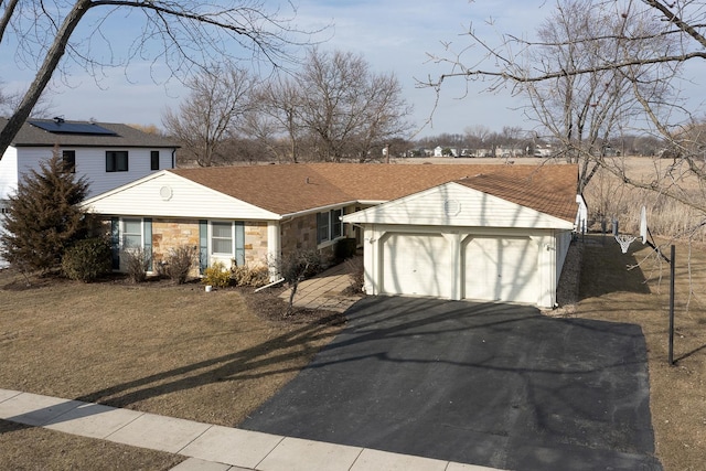 view of front of house with aphalt driveway, stone siding, an outdoor structure, and a garage