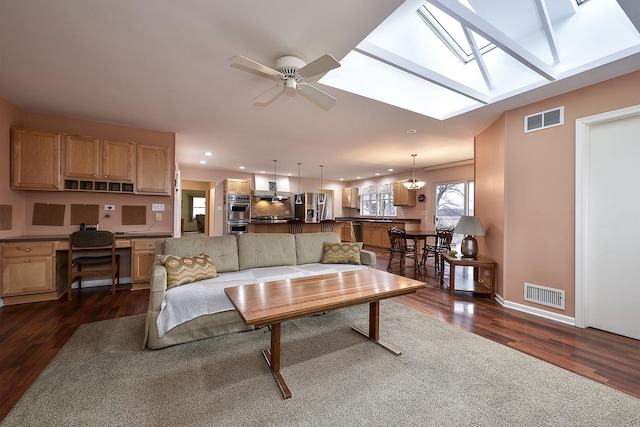 living room with a skylight, visible vents, and dark wood finished floors