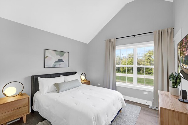 bedroom with lofted ceiling, baseboards, and wood finished floors