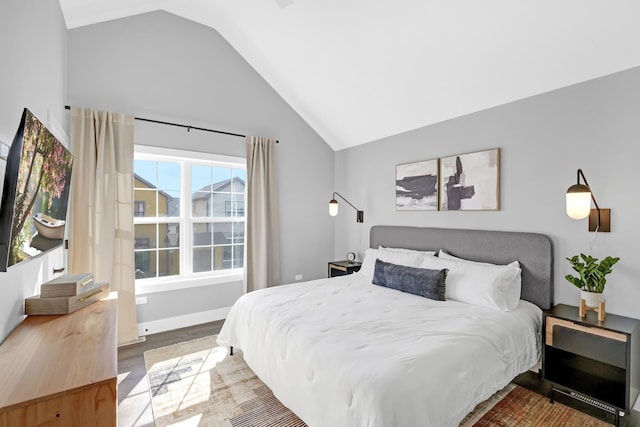 bedroom with vaulted ceiling, wood finished floors, and baseboards