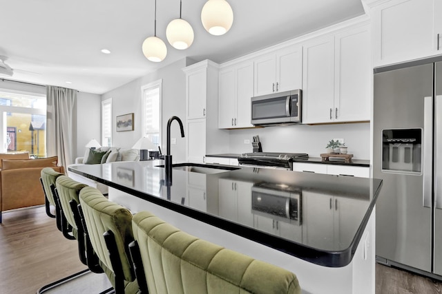 kitchen with appliances with stainless steel finishes, dark countertops, open floor plan, and a sink