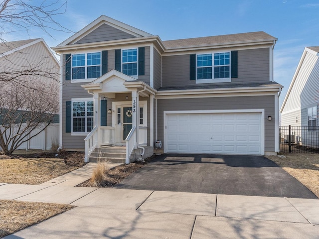 view of front facade with aphalt driveway, an attached garage, and fence