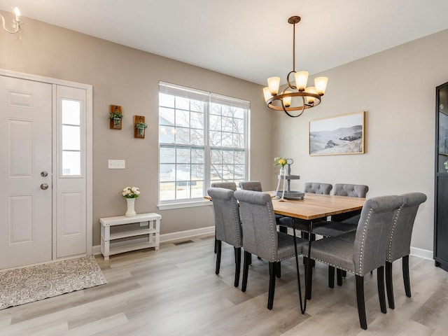 dining space featuring visible vents, light wood-style flooring, baseboards, and an inviting chandelier