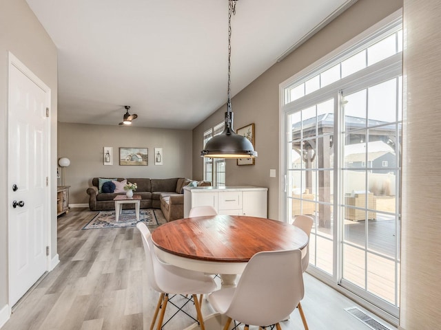 dining area with light wood-style floors, baseboards, and visible vents