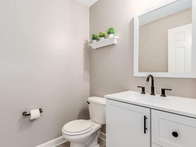 half bath featuring vanity, toilet, and baseboards