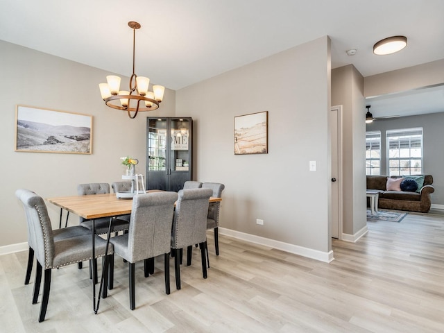 dining area featuring light wood-type flooring, a notable chandelier, and baseboards