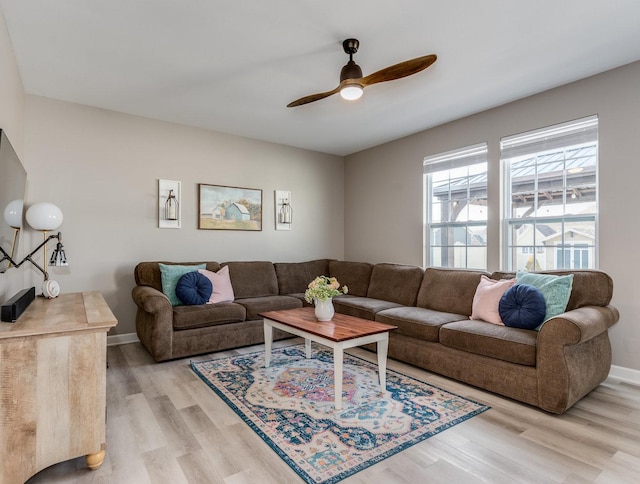 living room with light wood finished floors, baseboards, and a ceiling fan