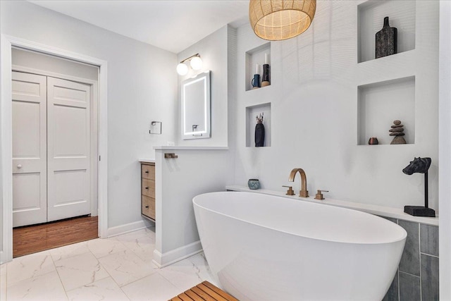 full bath with vanity, a soaking tub, baseboards, and marble finish floor