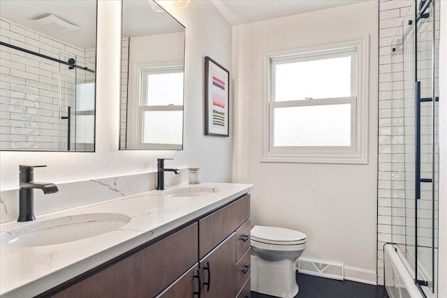 full bath featuring double vanity, visible vents, toilet, and a sink