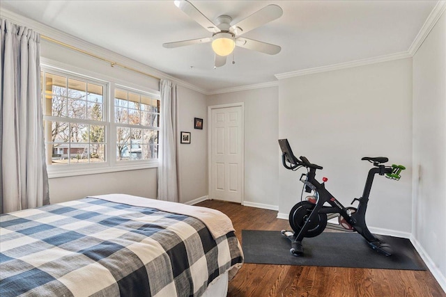 bedroom with baseboards, wood finished floors, a ceiling fan, and ornamental molding