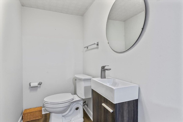 bathroom with toilet, vanity, and wood finished floors