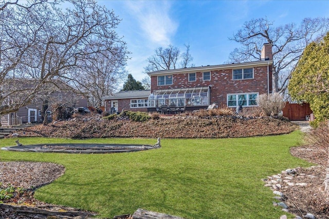 rear view of property featuring brick siding, a lawn, and a chimney