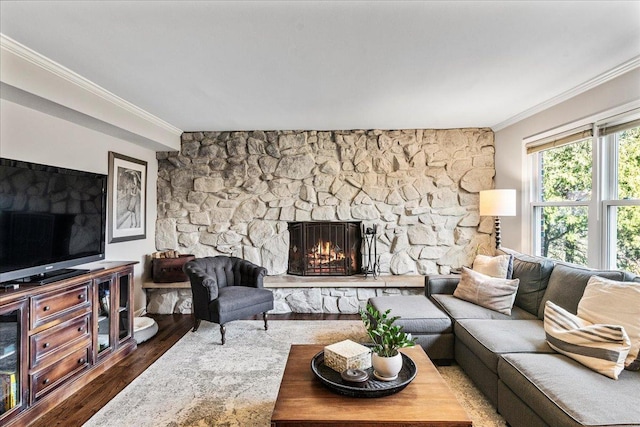 living room featuring a stone fireplace, crown molding, and wood finished floors