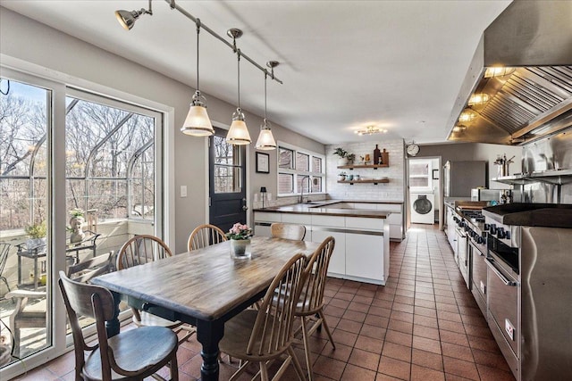 dining area featuring washer / clothes dryer and dark tile patterned floors