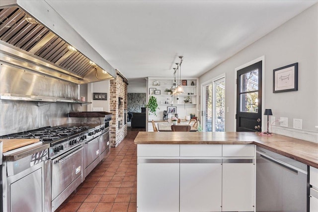 kitchen featuring tile patterned floors, custom exhaust hood, white cabinets, wood counters, and stainless steel dishwasher