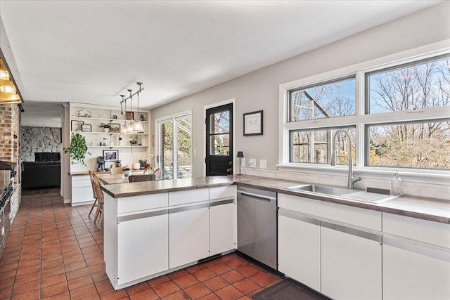 kitchen with dark tile patterned floors, dishwasher, a peninsula, white cabinets, and a sink