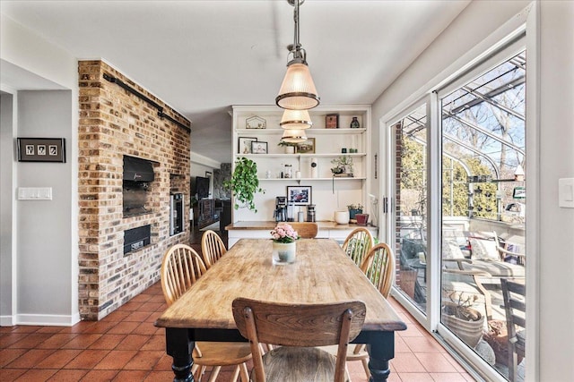 tiled dining space with a brick fireplace and baseboards