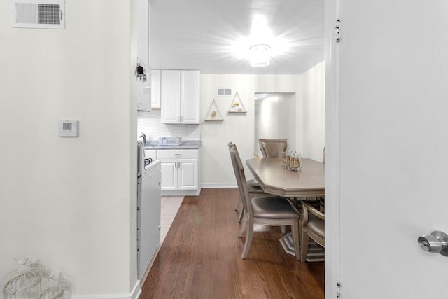 dining room with dark wood-style floors, visible vents, and baseboards