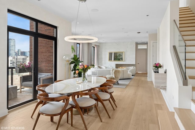 dining space featuring stairway, a large fireplace, a view of city, and light wood finished floors