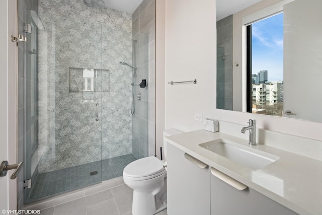 bathroom featuring vanity, tile patterned floors, toilet, and a stall shower