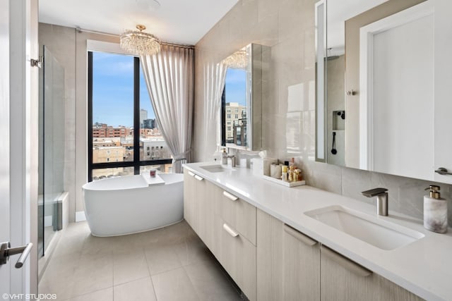 bathroom with a city view, tile walls, a freestanding bath, and a sink