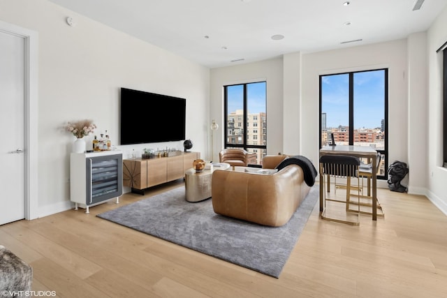 living area featuring wine cooler, light wood-style floors, and baseboards