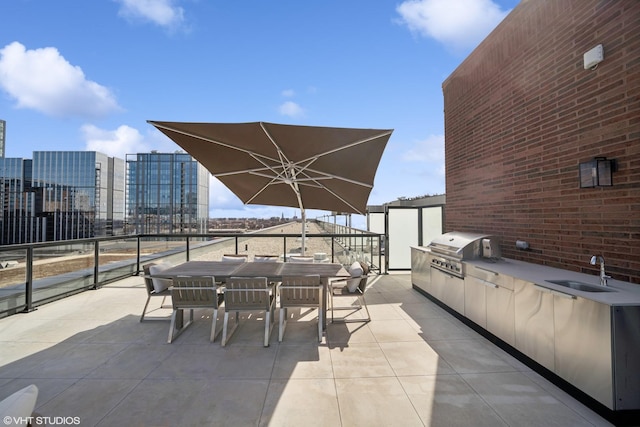 view of patio featuring outdoor dining space, exterior kitchen, a sink, grilling area, and a city view