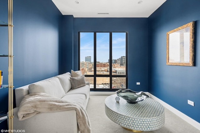 carpeted living room with a city view, visible vents, and baseboards