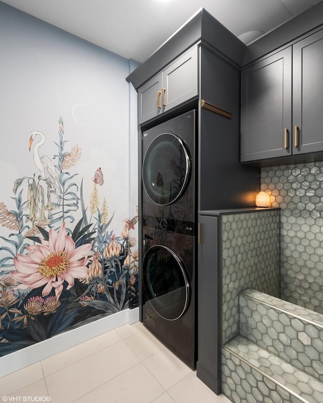 laundry area featuring cabinet space, stacked washer and clothes dryer, and tile patterned flooring