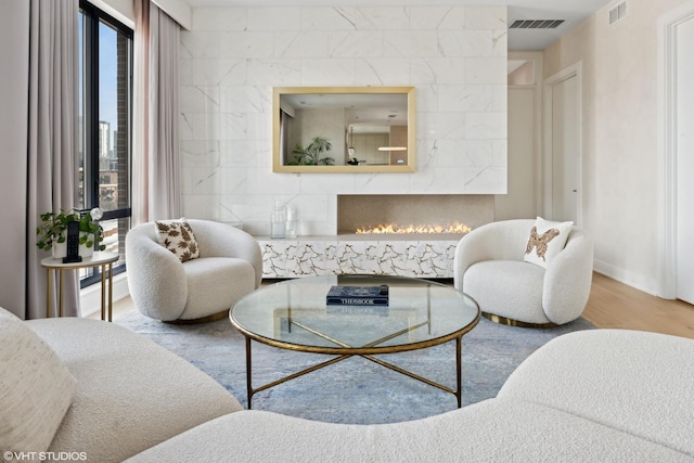 living area featuring wood finished floors, a fireplace, and visible vents