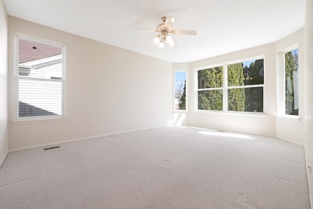 spare room with ceiling fan, carpet flooring, visible vents, and baseboards